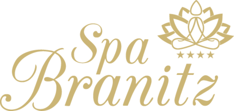 Logo mit dem Schriftzug „Spa Branitz“ in eleganter Schreibschrift, darüber stilisiertes Blütenmotiv, goldfarben auf weißem Hintergrund.