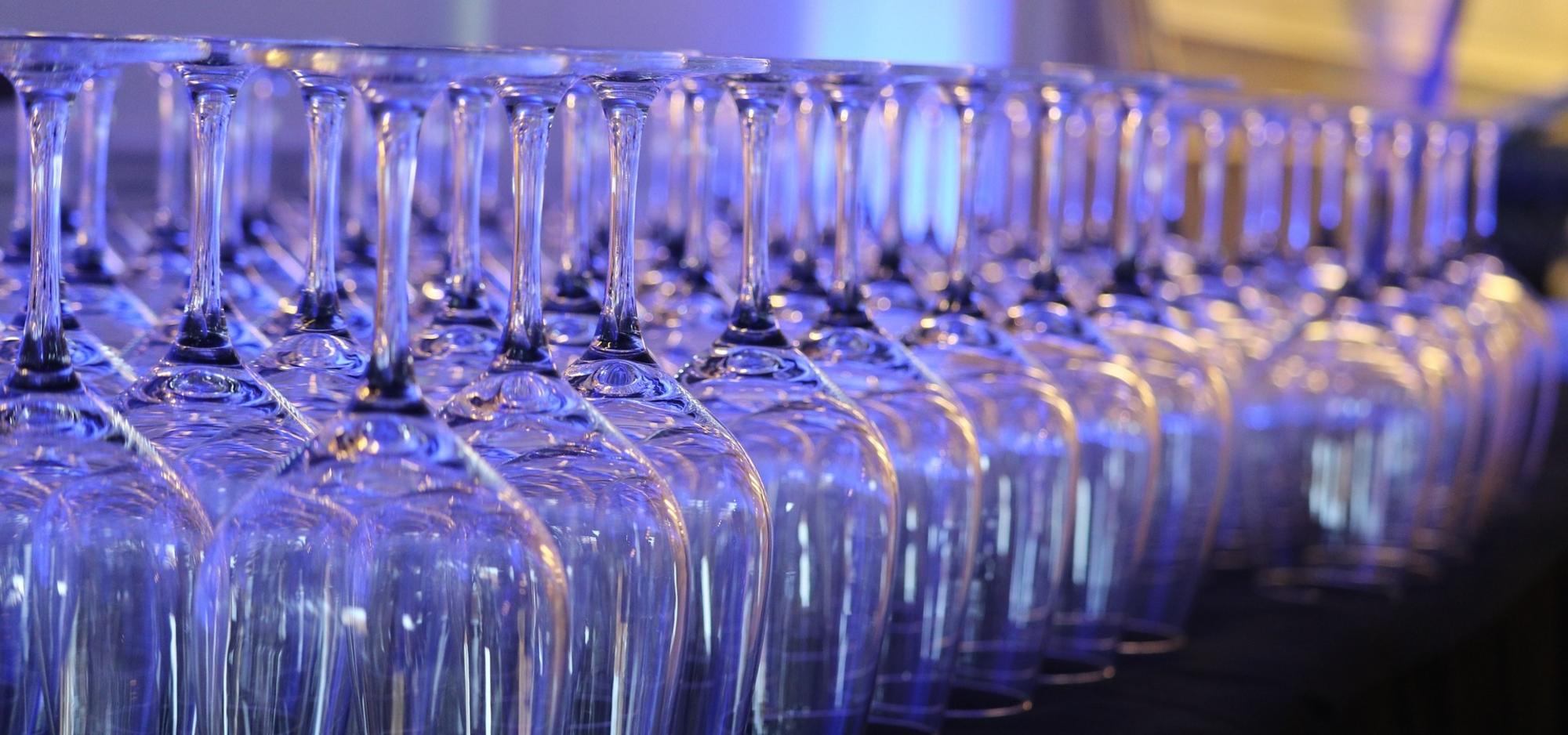 Zahlreiche leere Sektgläser ordentlich in Reihen auf einer Theke arrangiert – bereit für einen Empfang oder eine Feier.