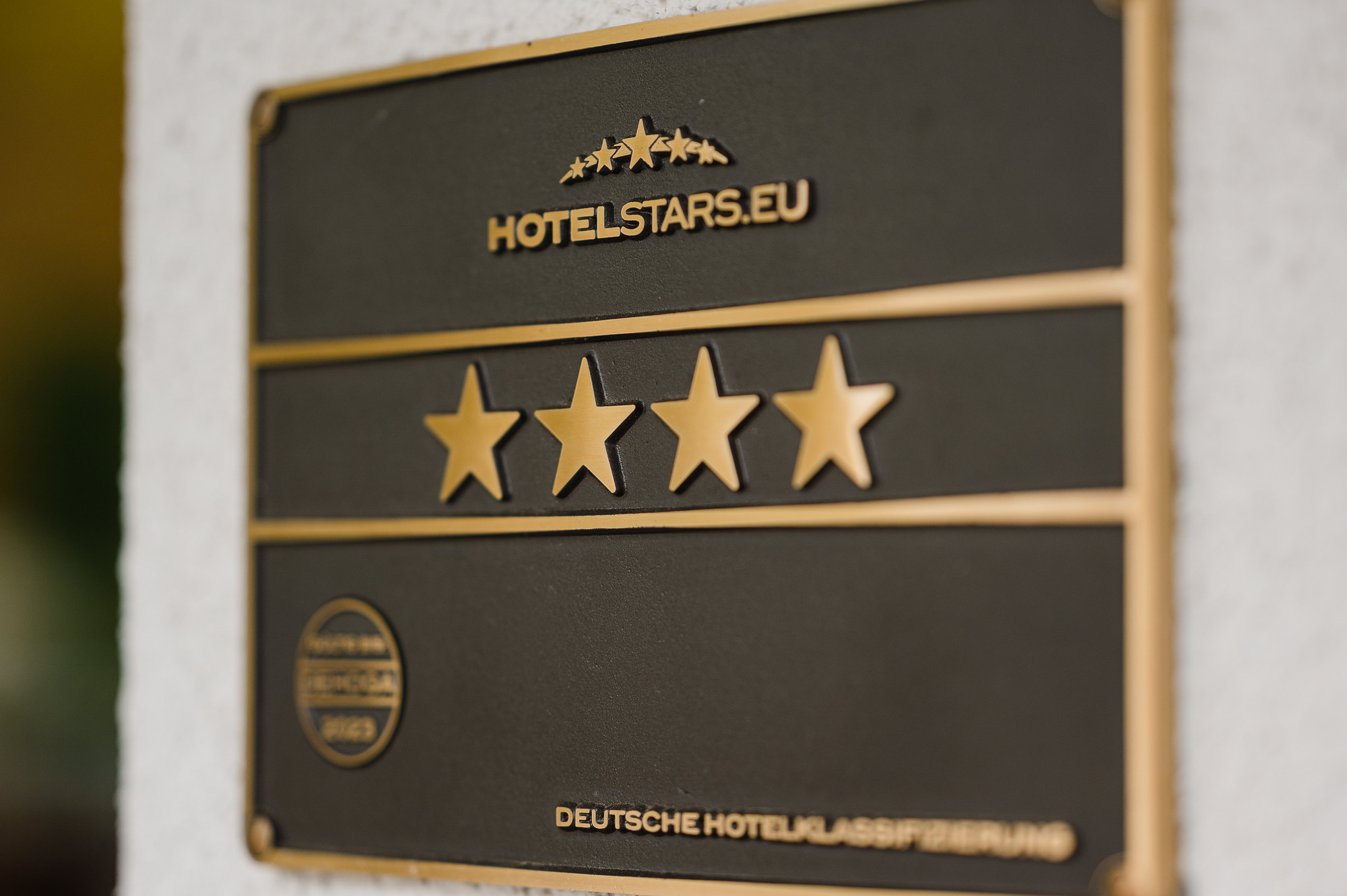 Plakette mit vier Sternen und goldener Beschriftung auf dunklem Hintergrund an einer Wand